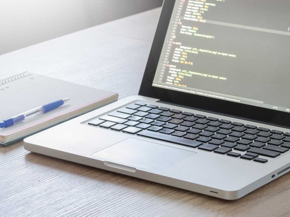 Laptop showing screen with HTML code for Web Design